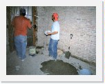 Juan and Cheche sealing the door frame * Juan and Cheche doing the fun part of installing a door - throwing cement to fill in the gaps around the edge of the door frame. * 570 x 441 * (129KB)